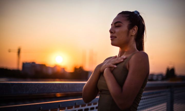 une femme pratiquant la respiration wim hof sous un couché de soleil